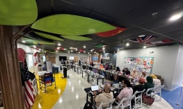 a group of people sitting in chairs in a room with tables and chairs