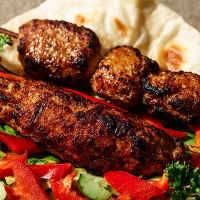meat on skewers atop pita bread, surrounded by vegetables