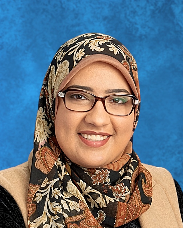 Photo of smiling woman with rust, black, and beige hijaab