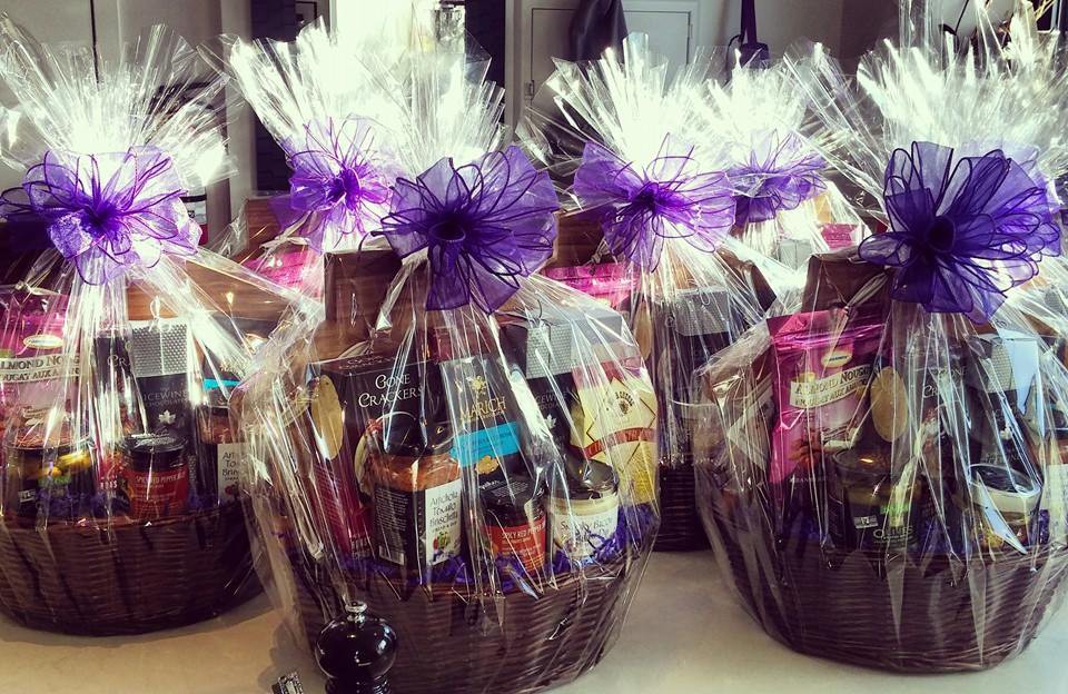 Dark brown wicker baskets filled with treats and wrapped in white tulle and purple bow